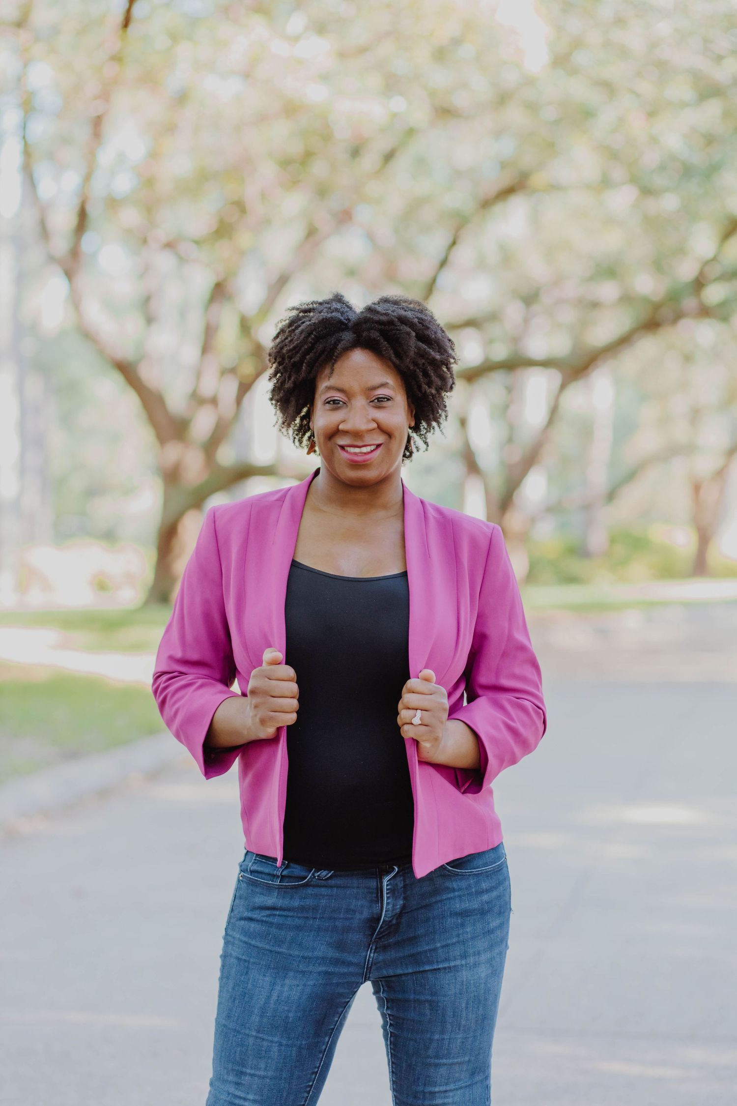 A casual outdoor portrait featuring bright pink blazer and jeans.