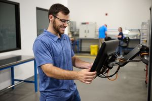 Man in casual attire working with electronic equipment in industrial workspace.