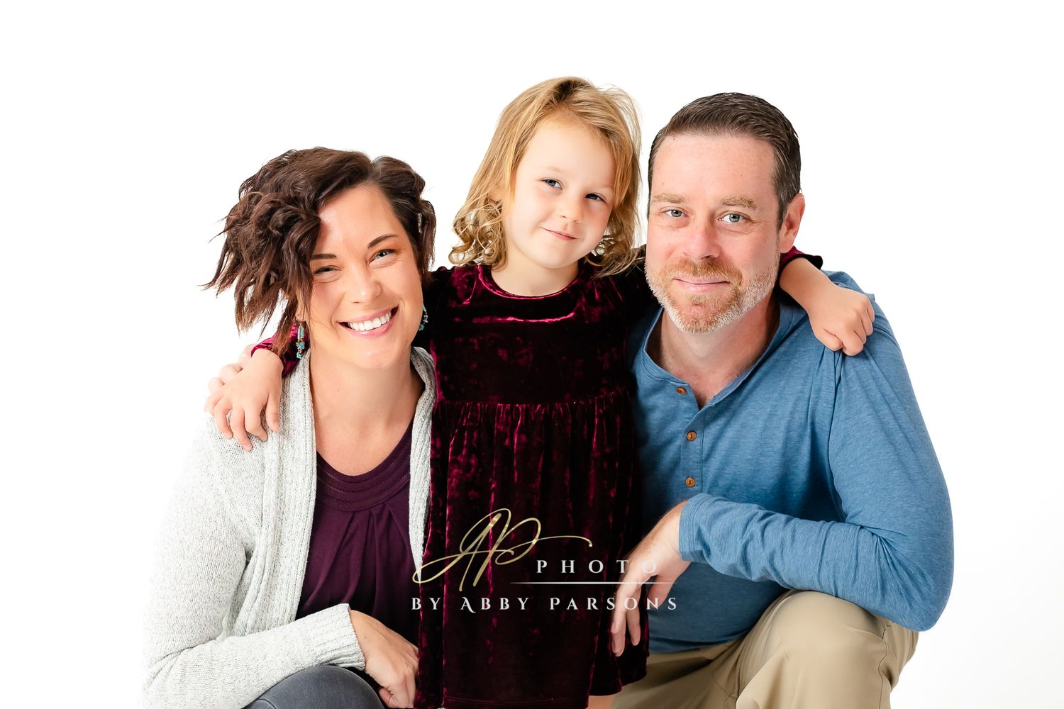 Portrait of three people wearing casual attire against a white background sharing warm smiles.