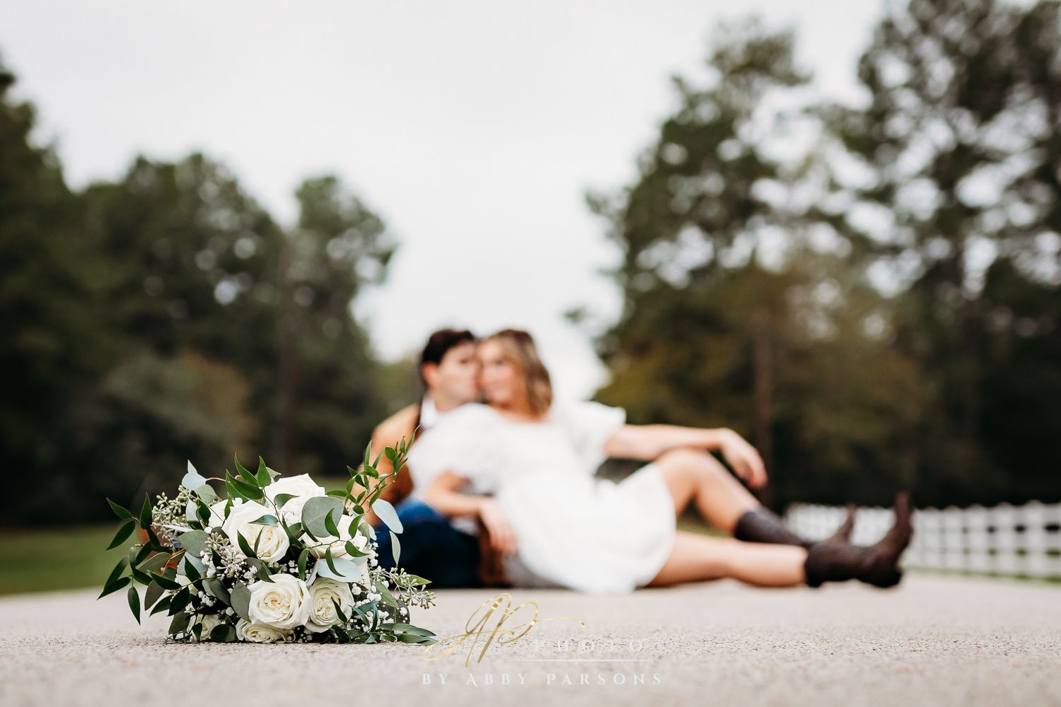Wedding bouquet with white roses in foreground with a blurred romantic scene in the background.