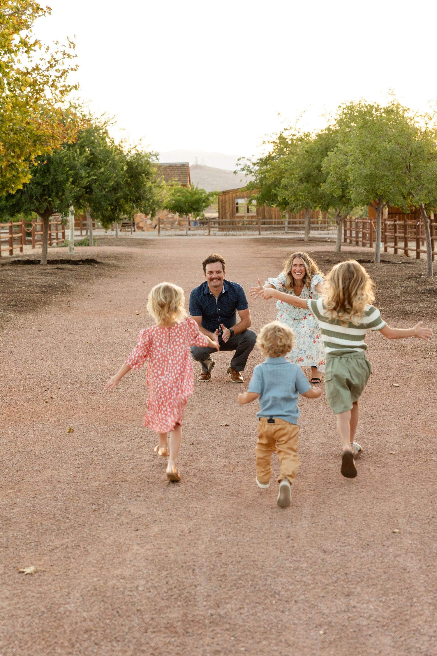 a family with 3 children getting their photo taken laughing run 2 each other in desert of Southern Utah. St. George Utah family photographer