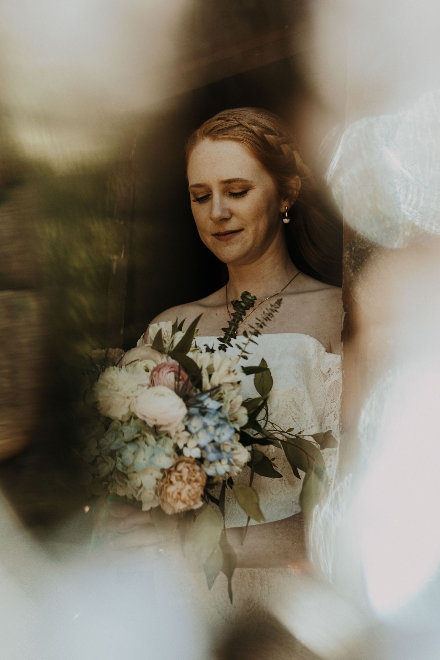 A soft, ethereal bridal portrait with delicate pastel bouquet through dreamy lens blur.