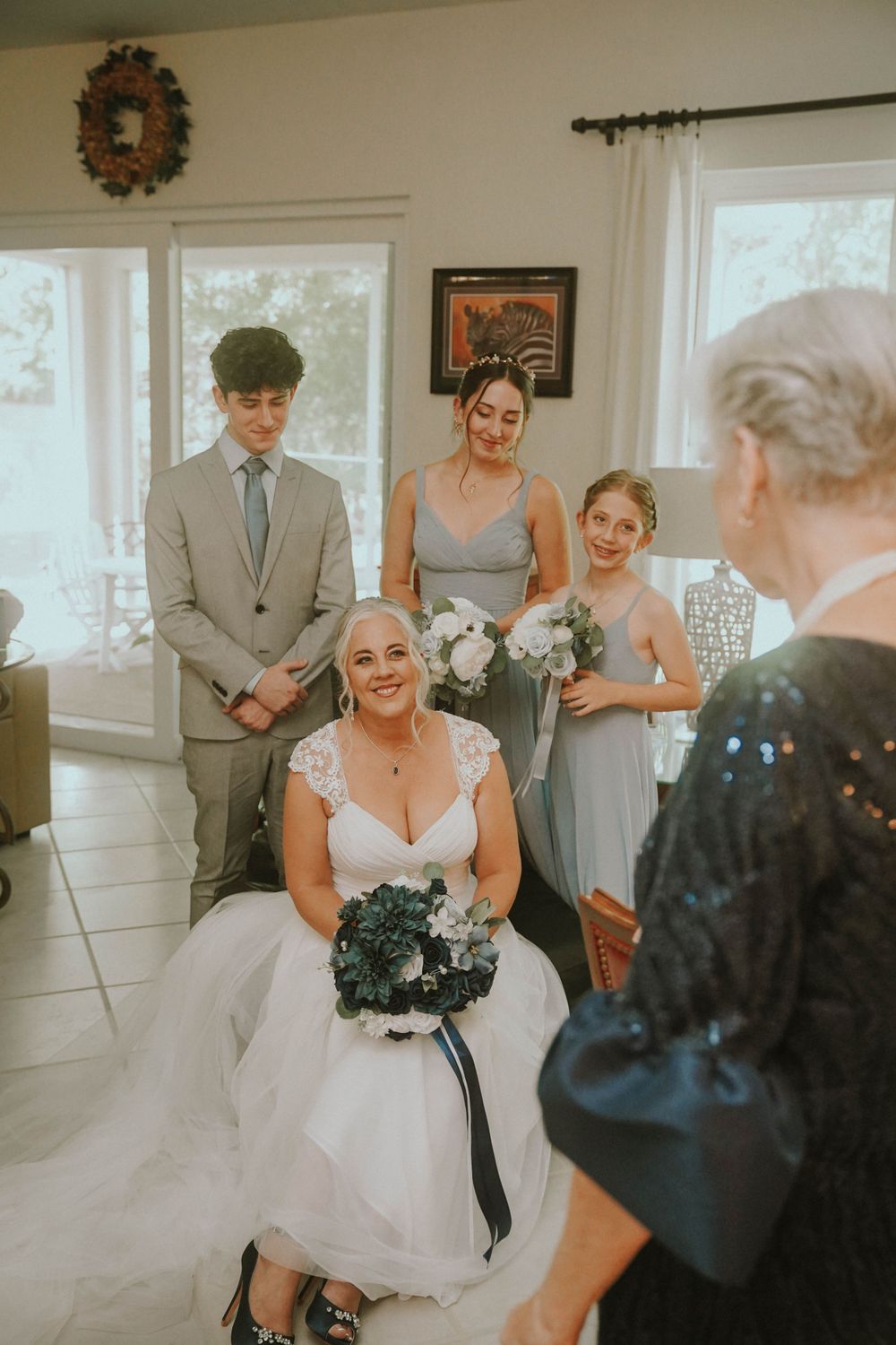 Wedding party gathered in sunlit room during pre-ceremony preparations.