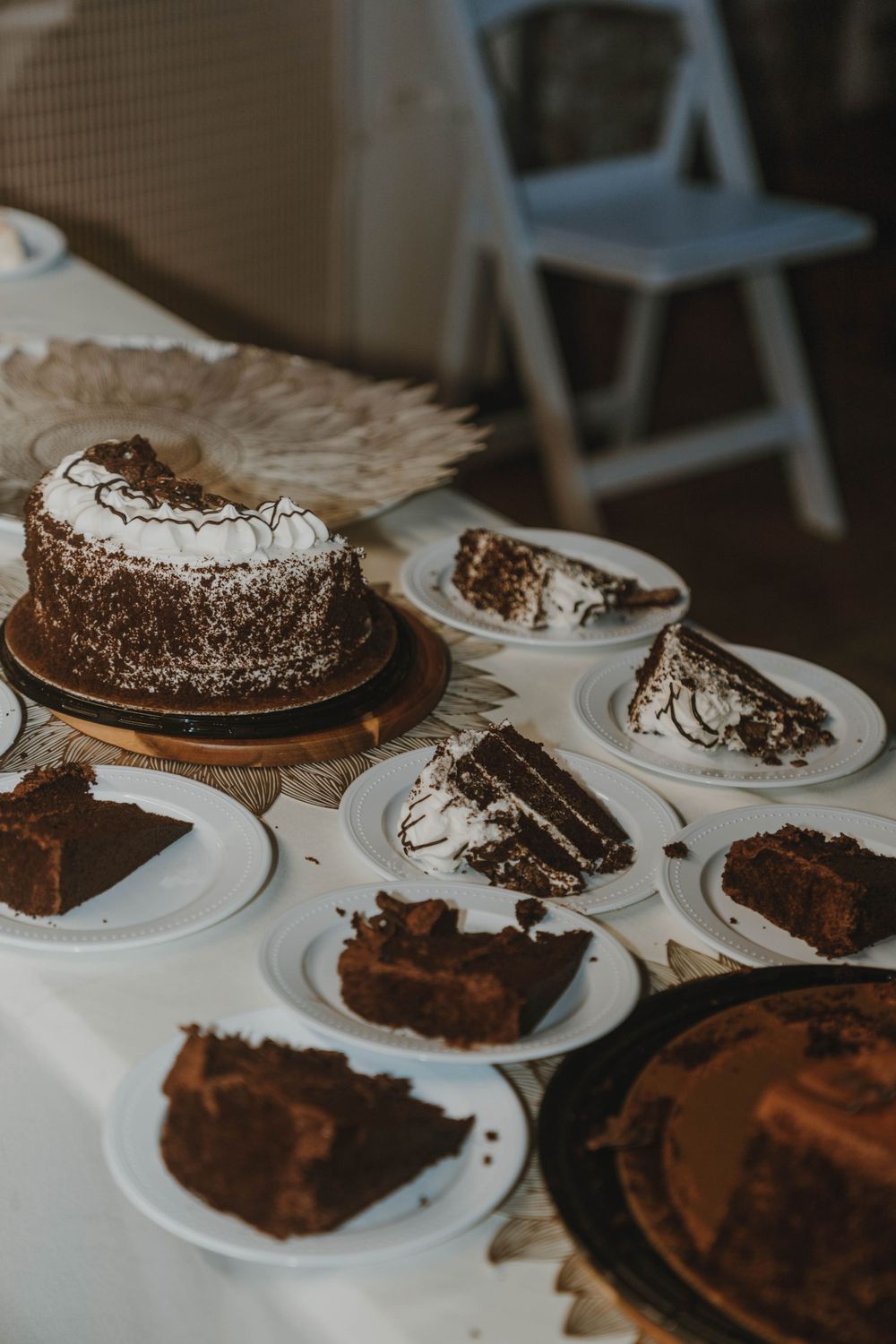 Elegant chocolate and vanilla cakes with frosting arranged on a white tablecloth at a special event.