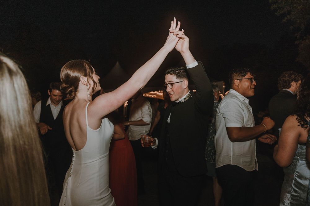 Celebratory dance moves at a wedding reception with guests on the dance floor.