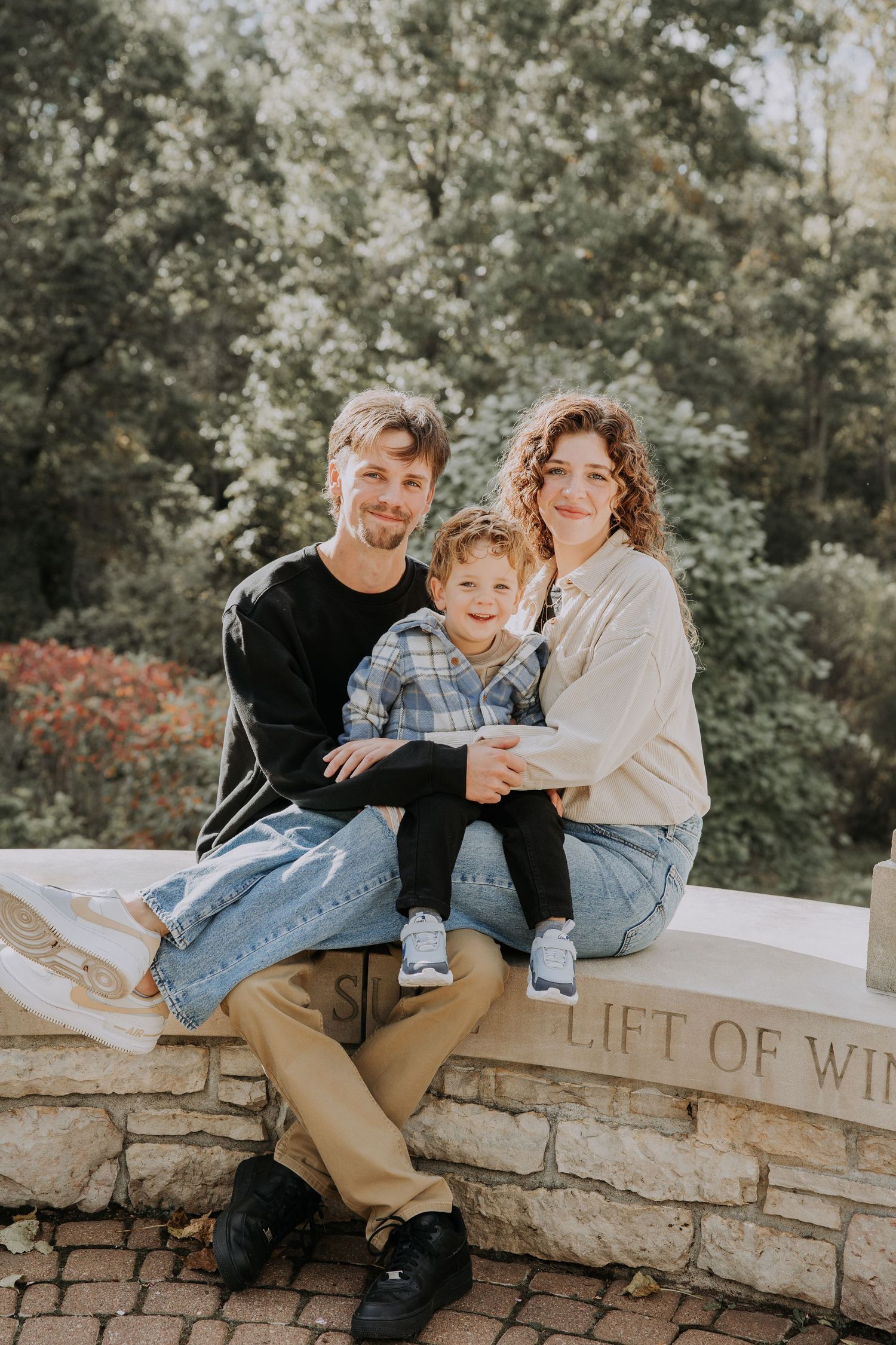 Family enjoying a playful moment together on a wooded path during golden hour.
