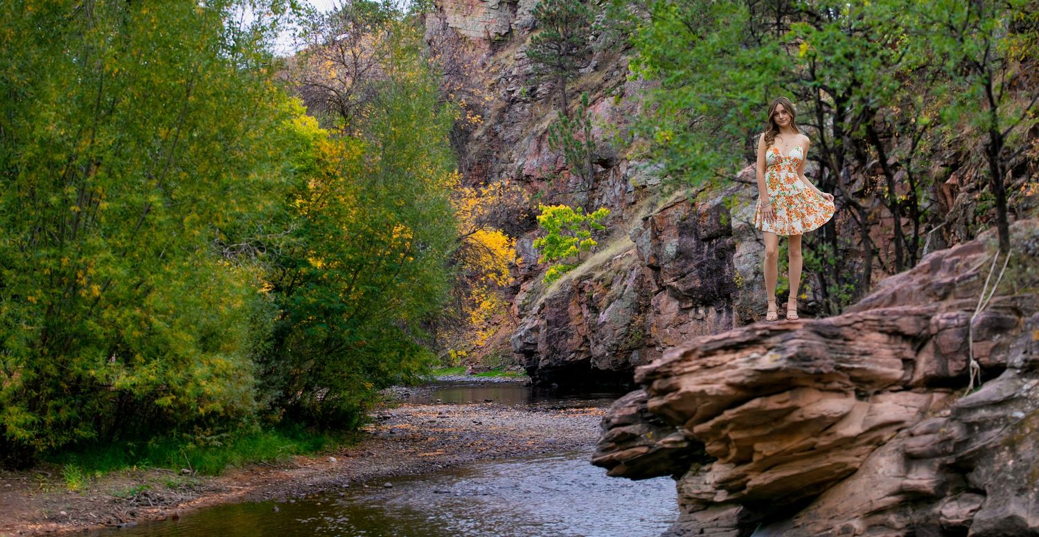 A scenic hiking trail winds through rocky outcroppings and fall foliage along a creek bed in a state park.