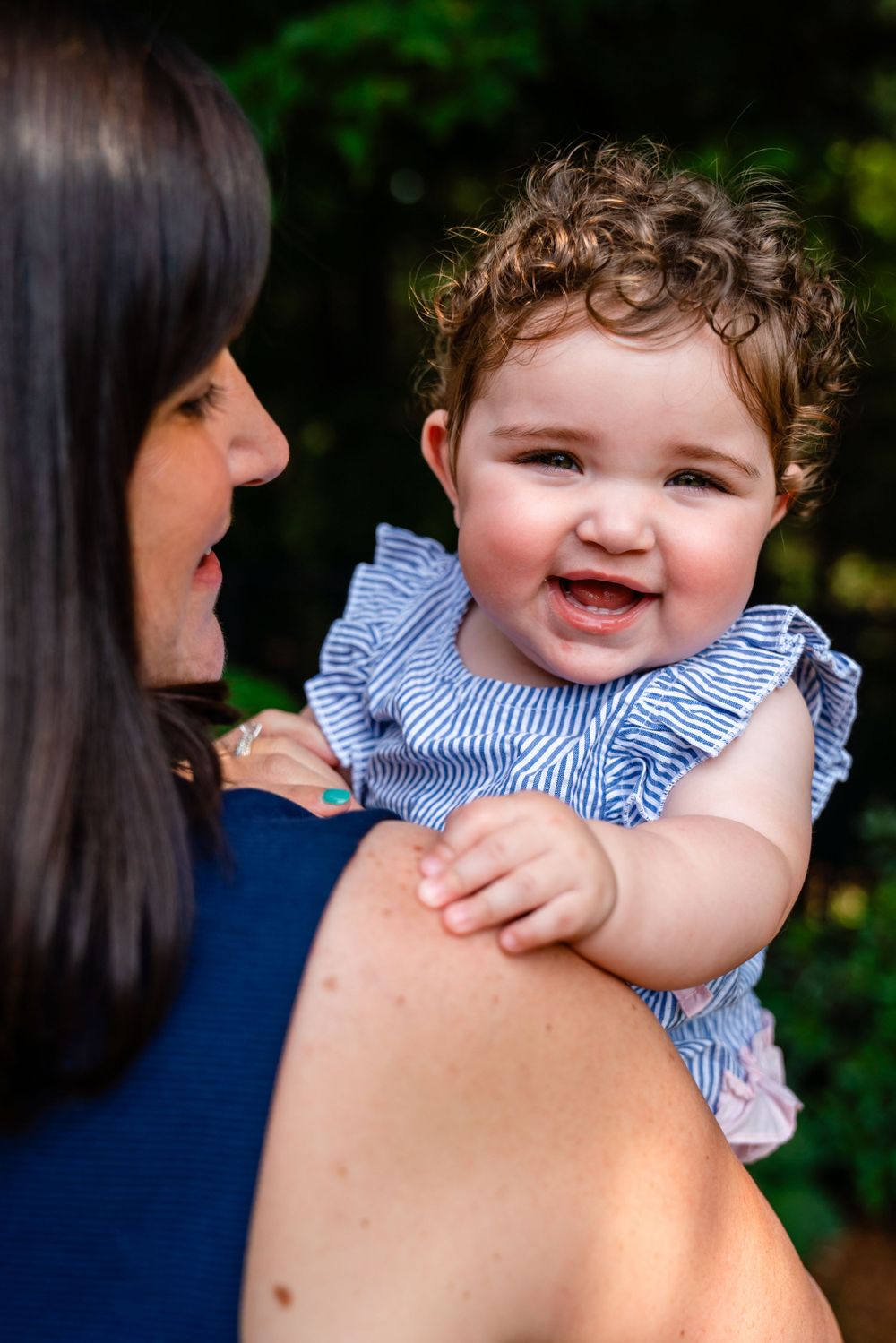 Happy baby in blue ruffled outfit smiling brightly outdoors.