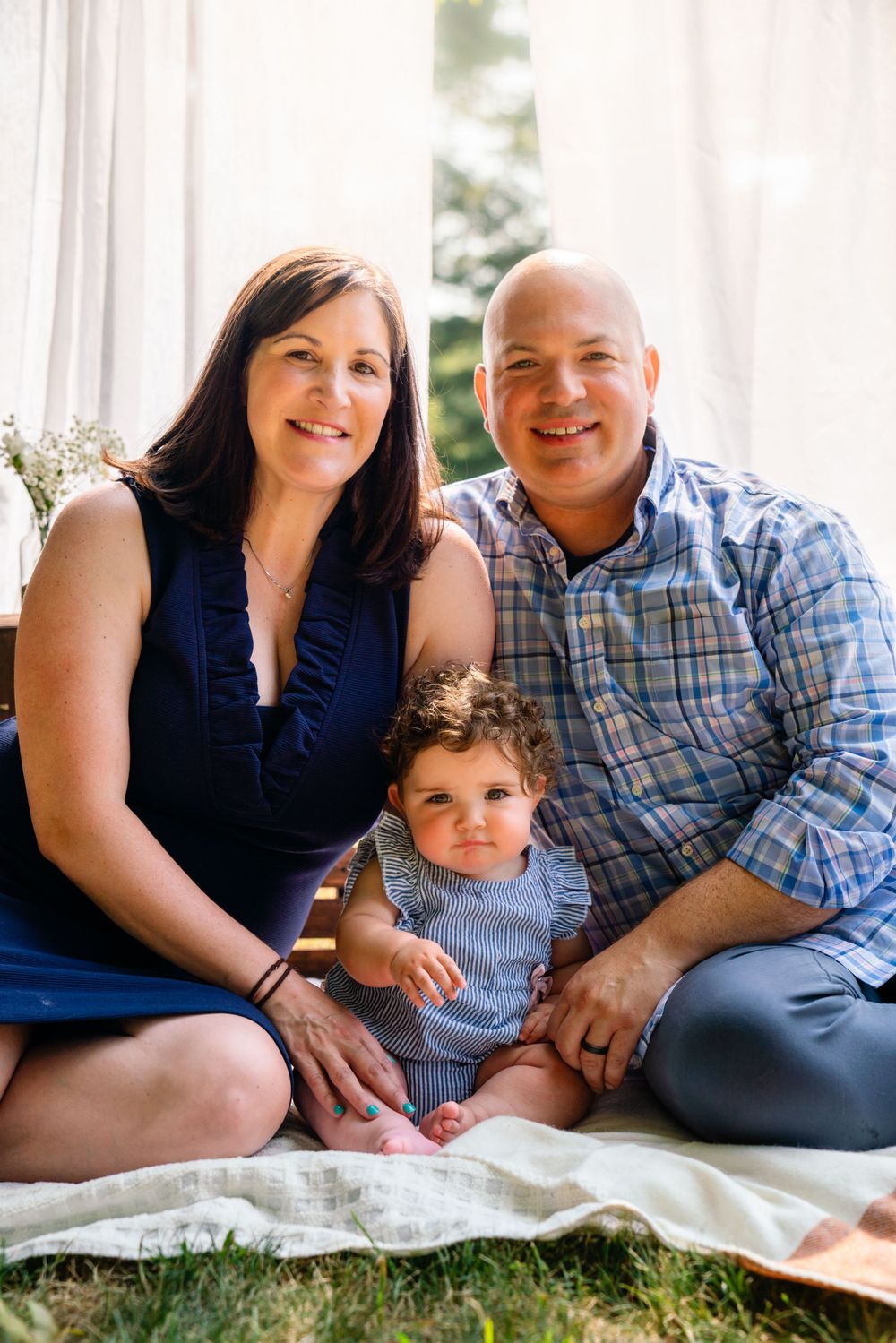 Family sitting together on white blanket for indoor portrait session.
