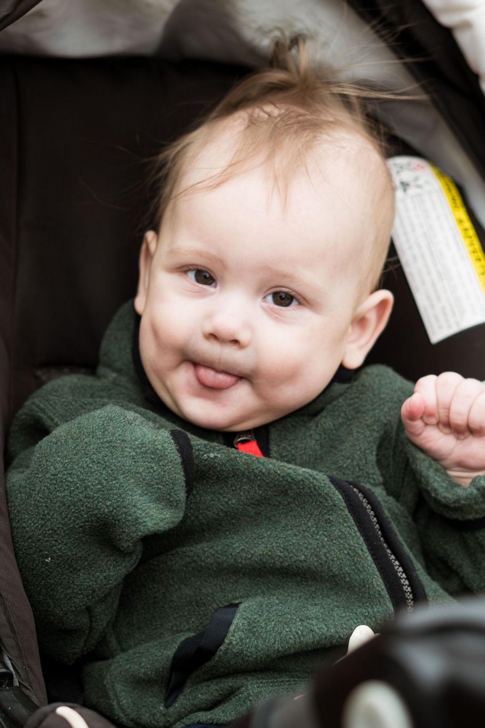 A sequence of candid shots showing a baby in a dark green fleece outfit.
