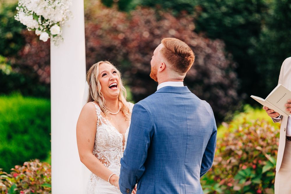 A couple shares joyful moments during their wedding celebration in a lush garden setting with white floral decor.