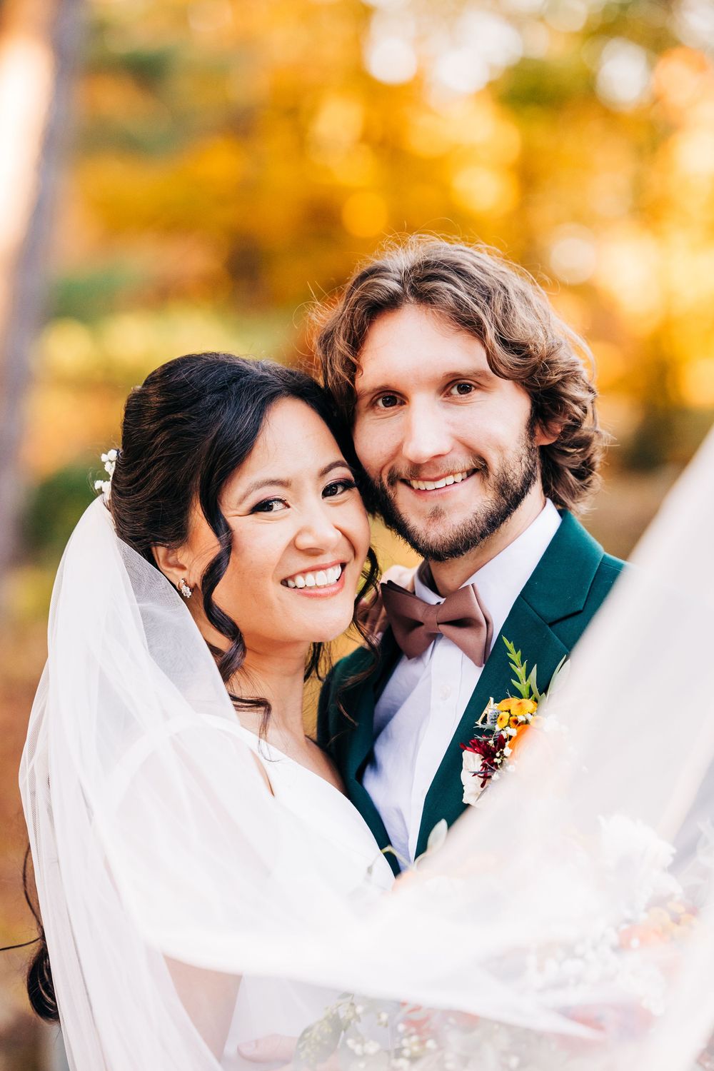 A happy couple shares romantic moments in a fall setting with golden foliage in the background.
