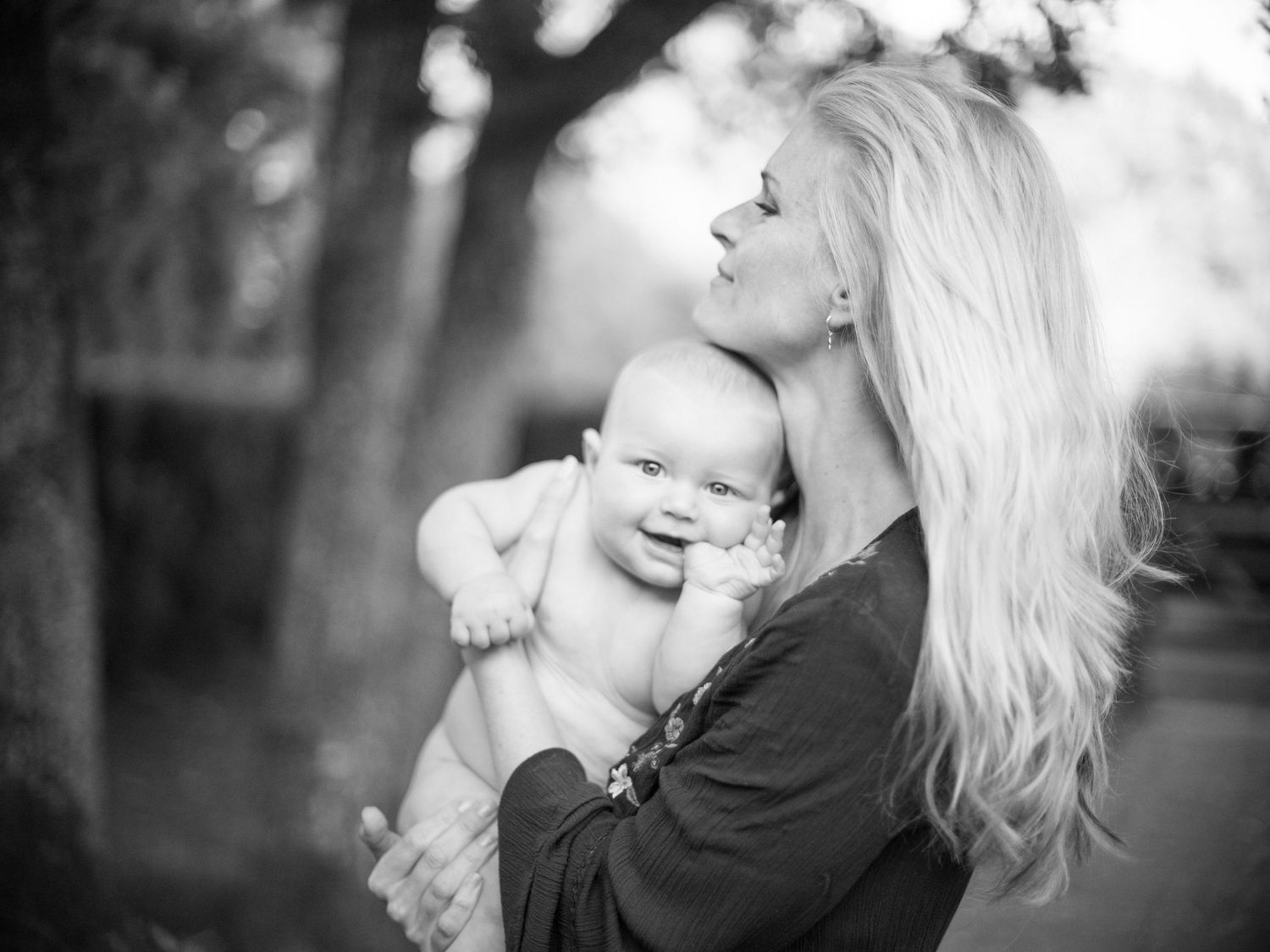 A series of black and white photos showing a parent holding and kissing a baby in various tender moments.