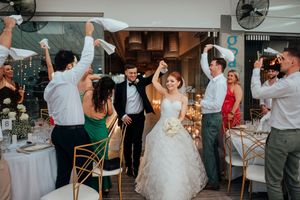Wedding guests dance and celebrate on a dance floor during a reception party at an indoor venue.