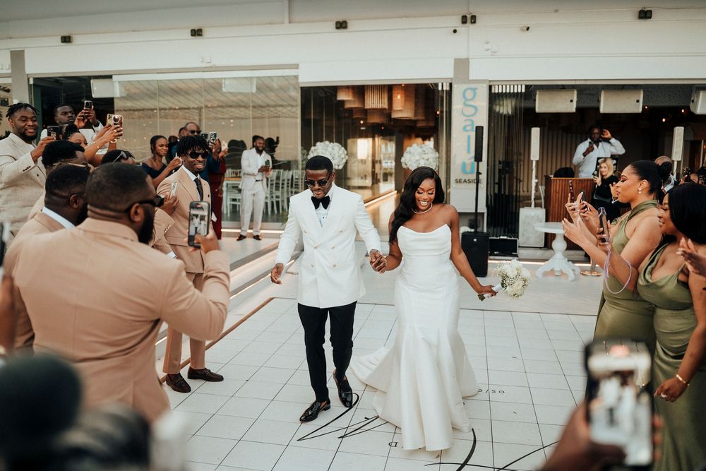 Wedding guests dance and celebrate together on a tiled dance floor at an indoor reception venue.