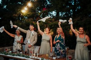 Wedding guests dance and celebrate during an outdoor evening reception with string lights overhead.