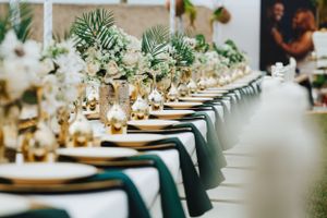 Elegant wedding reception table setup with gold decorations, floral centerpiece, and stylish tableware.