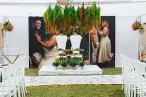 Beautifully decorated wedding altar with hanging greenery, floral arrangements, and white chairs arranged for a ceremony.