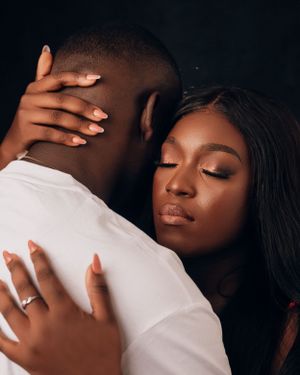 Warm, intimate studio portrait of a couple with the woman leaning her head on the man's shoulder.