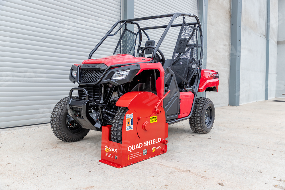 Red Honda Pioneer UTV with protective roll cage frame parked next to a safety equipment box.
