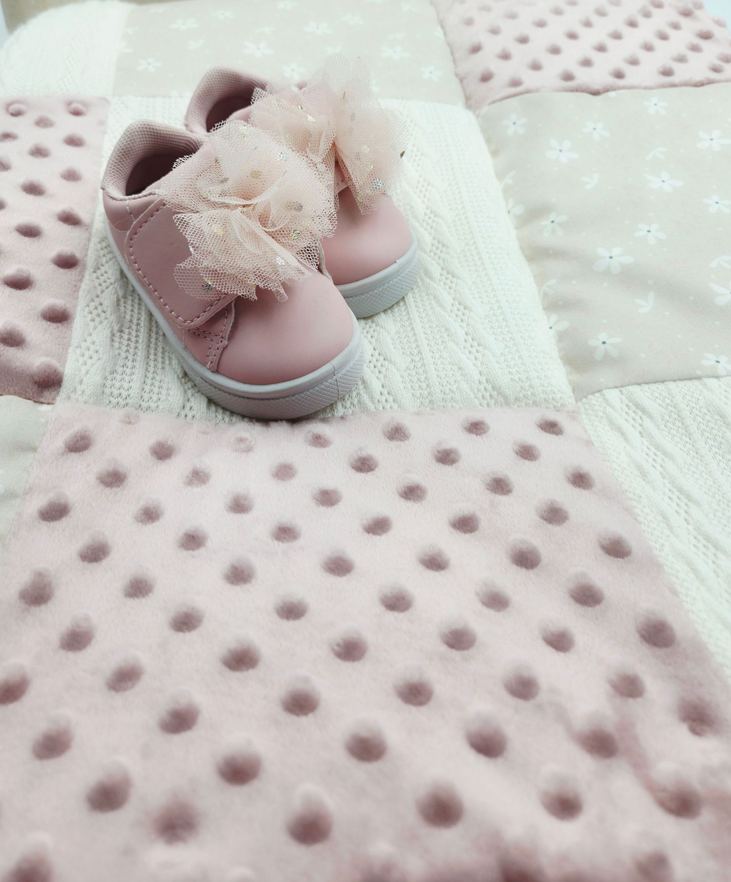 Close-up of pink minky dot fabric texture with baby shoe detail.