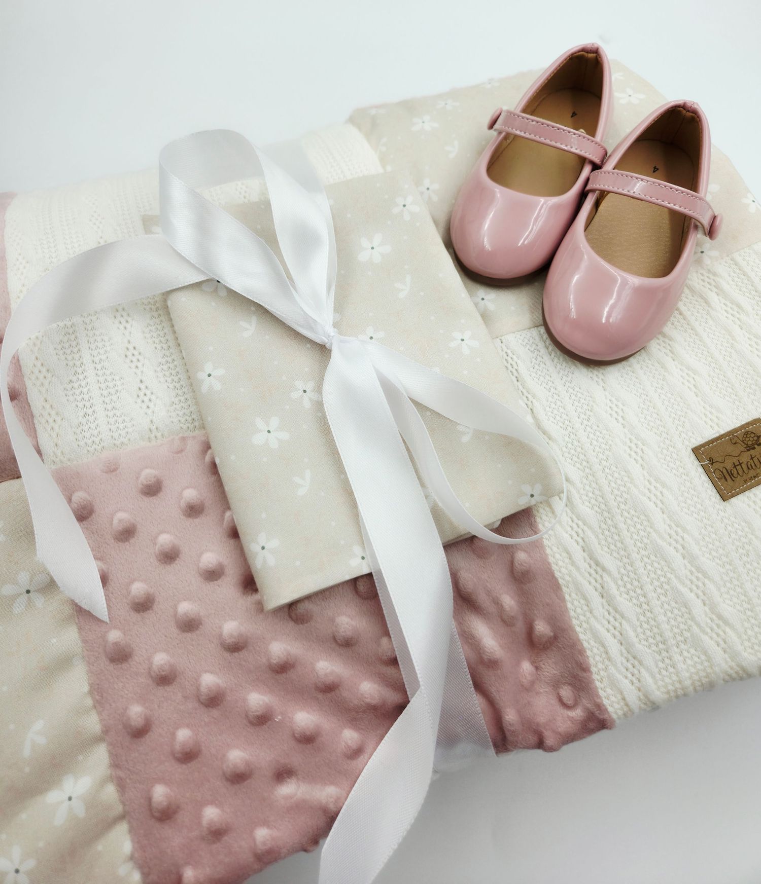 Baby blanket set featuring pink minky fabric and white textiles with delicate pink shoes.