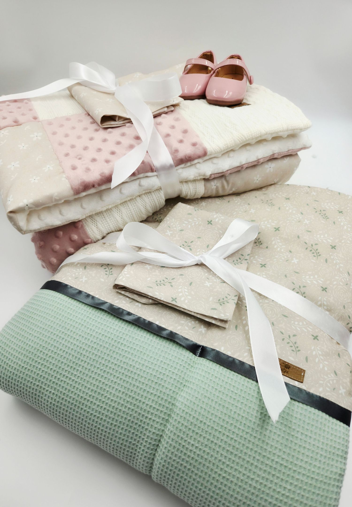 Mint green and cream baby blanket set with floral patterns and white ribbon accents.