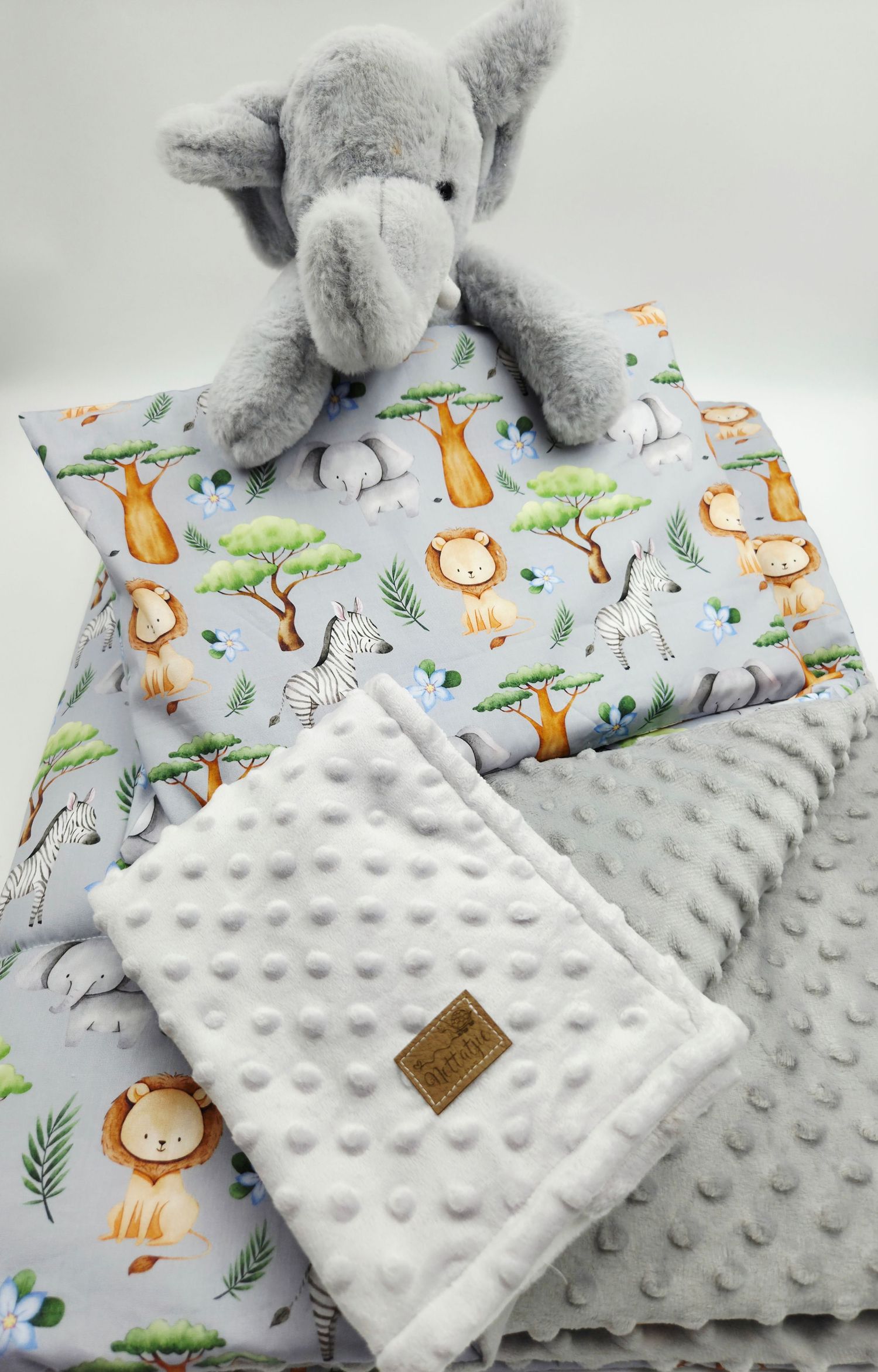 Gray minky blanket with safari animal print and plush elephant toy.