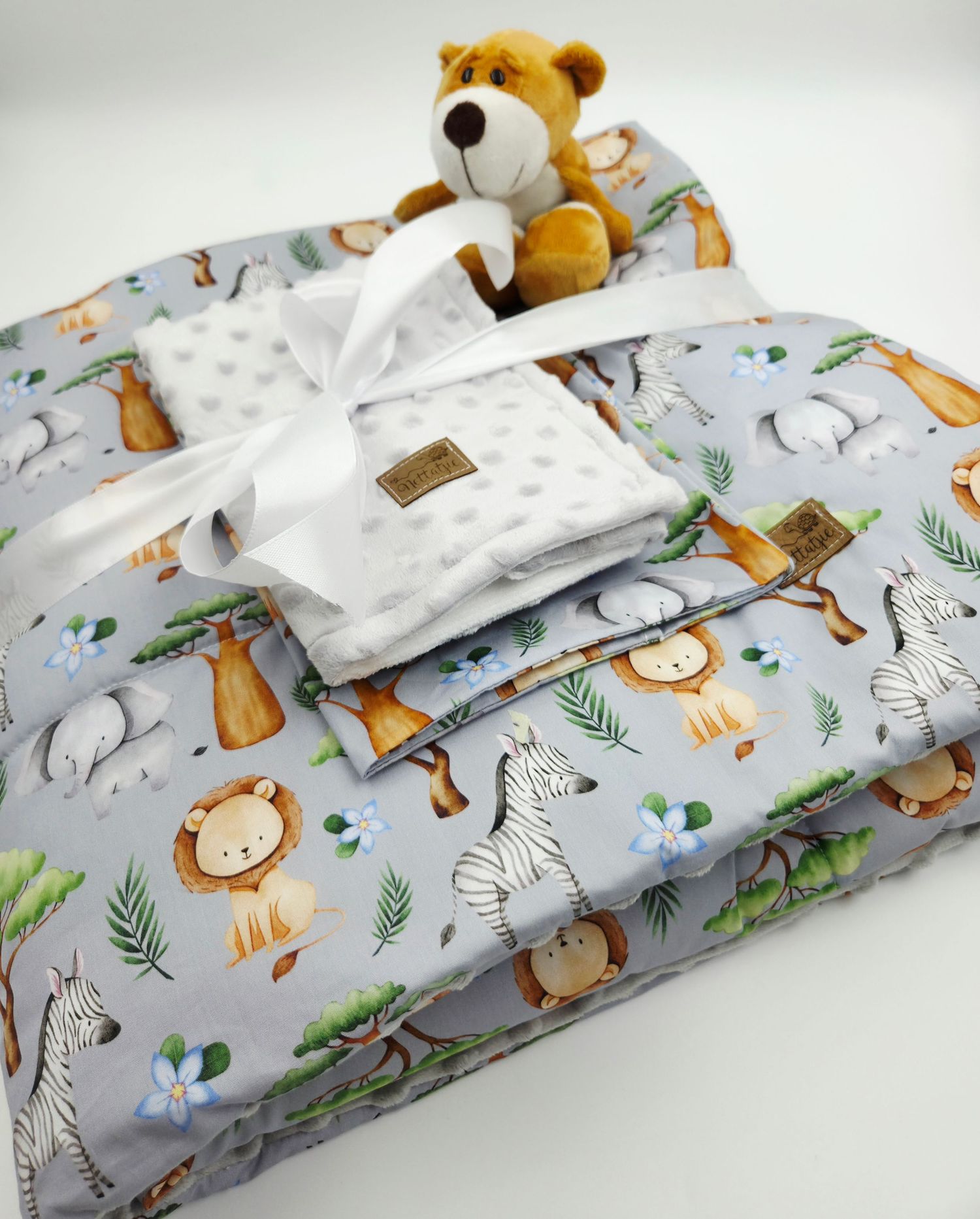 Baby blanket set featuring safari animals and white minky fabric with stuffed lion toy.