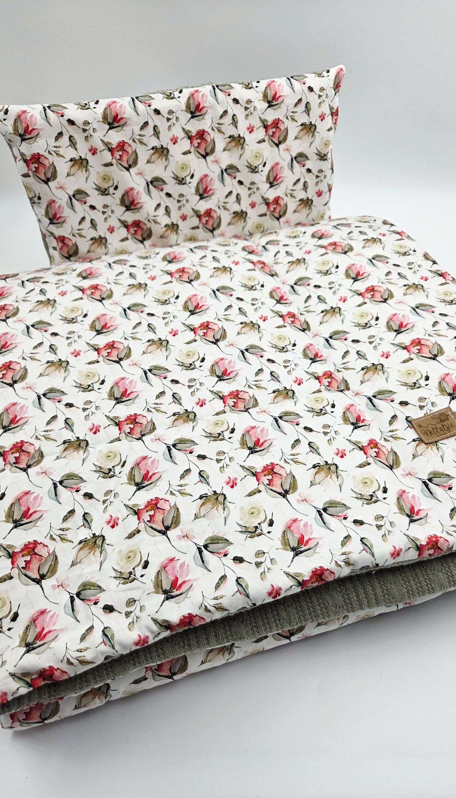 Baby blanket with delicate pink floral pattern on white background.
