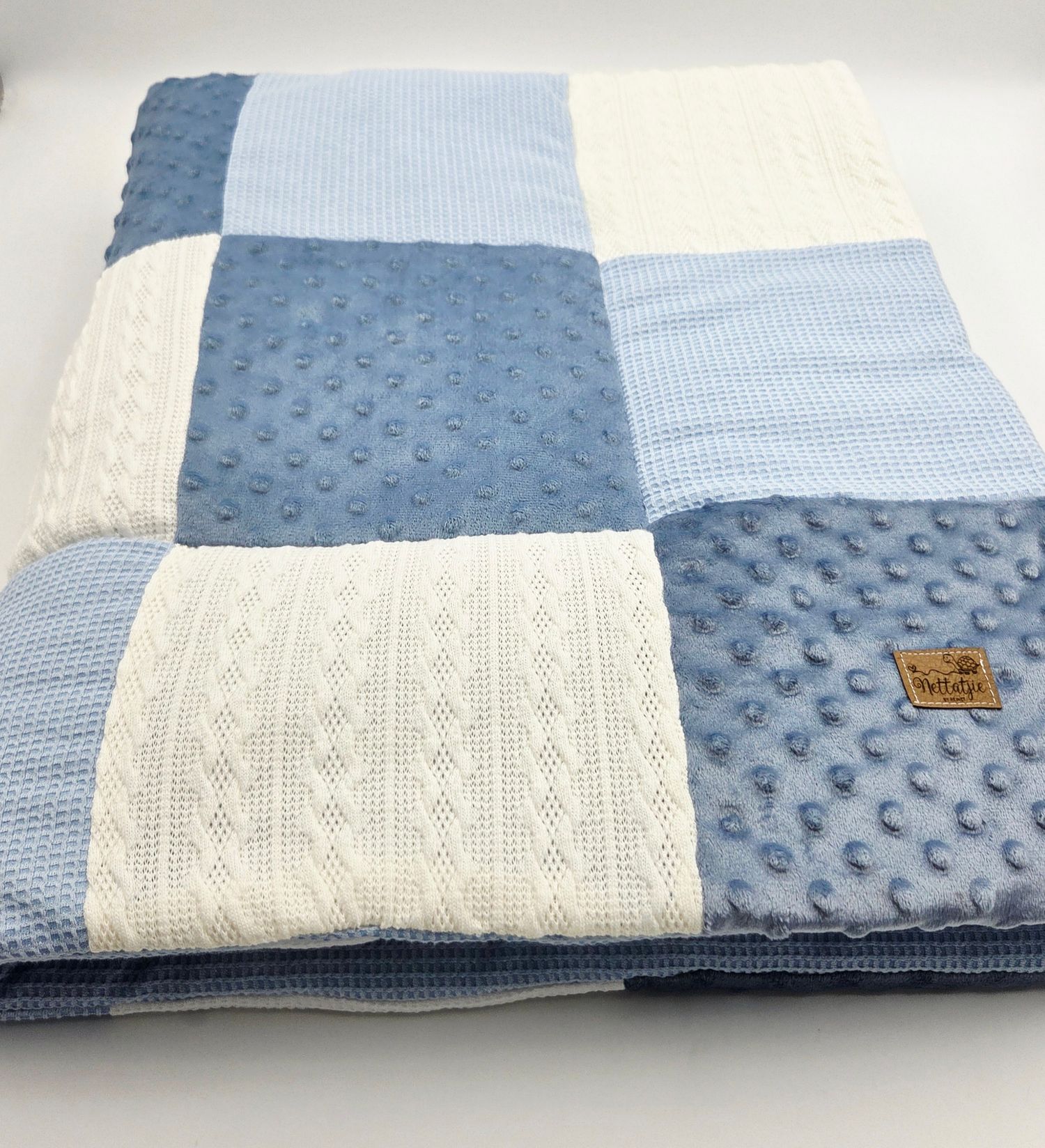 Blue and cream colored baby blanket with textured minky fabric and cable knit patterns.