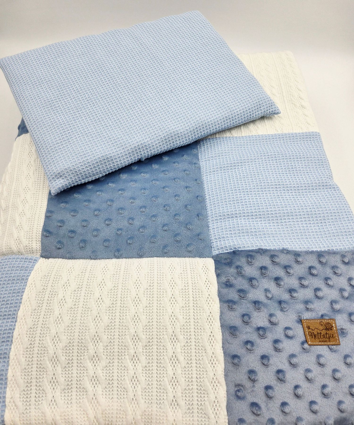 Baby blanket combining light blue minky dots, gingham, and cream cable knit patterns.