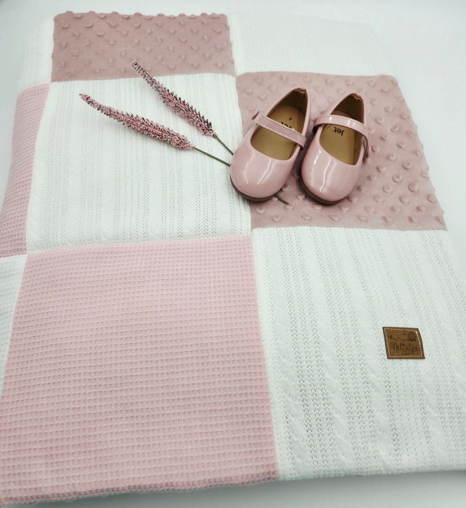 Soft pink baby blanket featuring textured minky fabric and white cable knit sections.