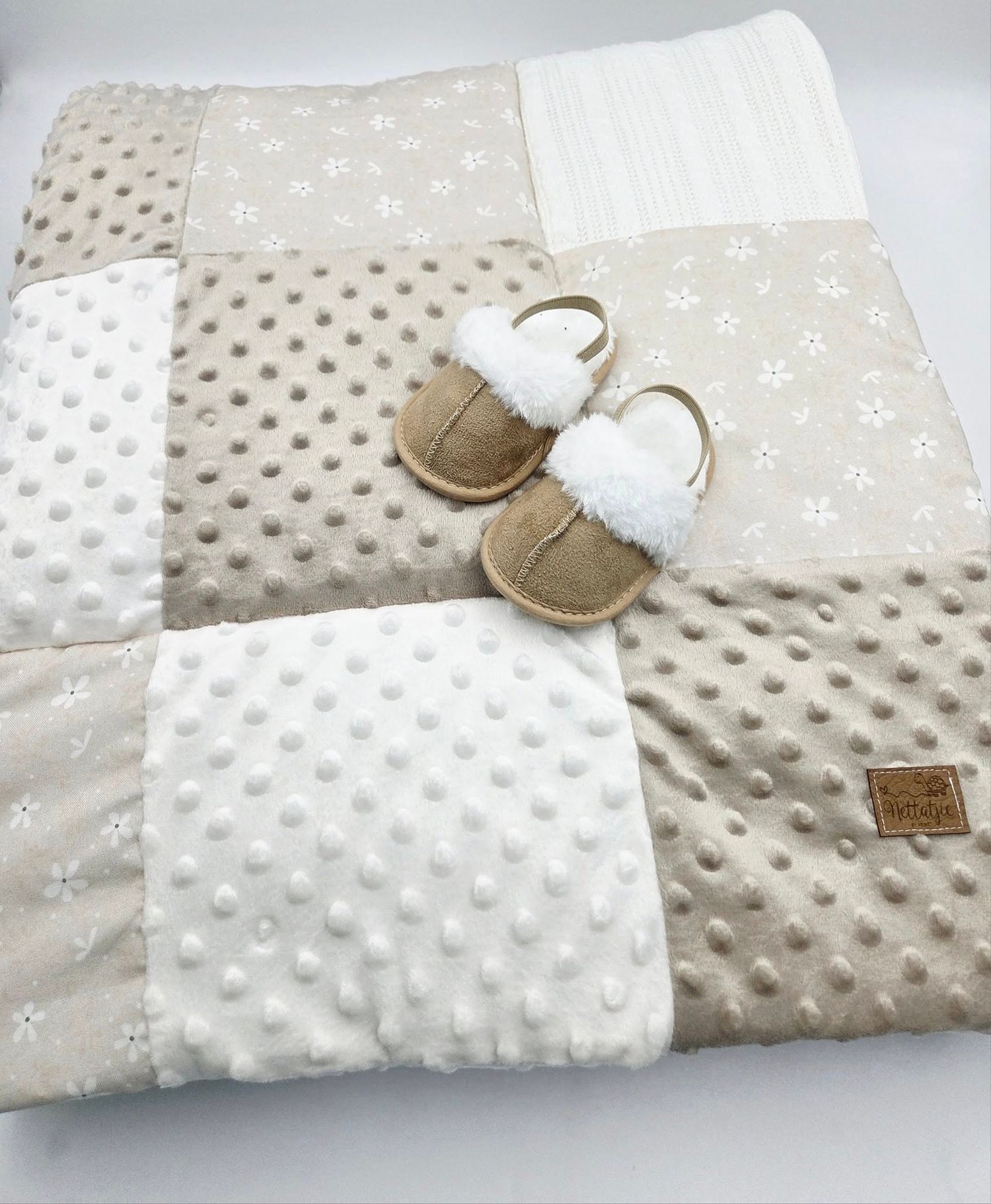 Cozy beige and white patchwork baby blanket with soft minky fabric and decorative booties.