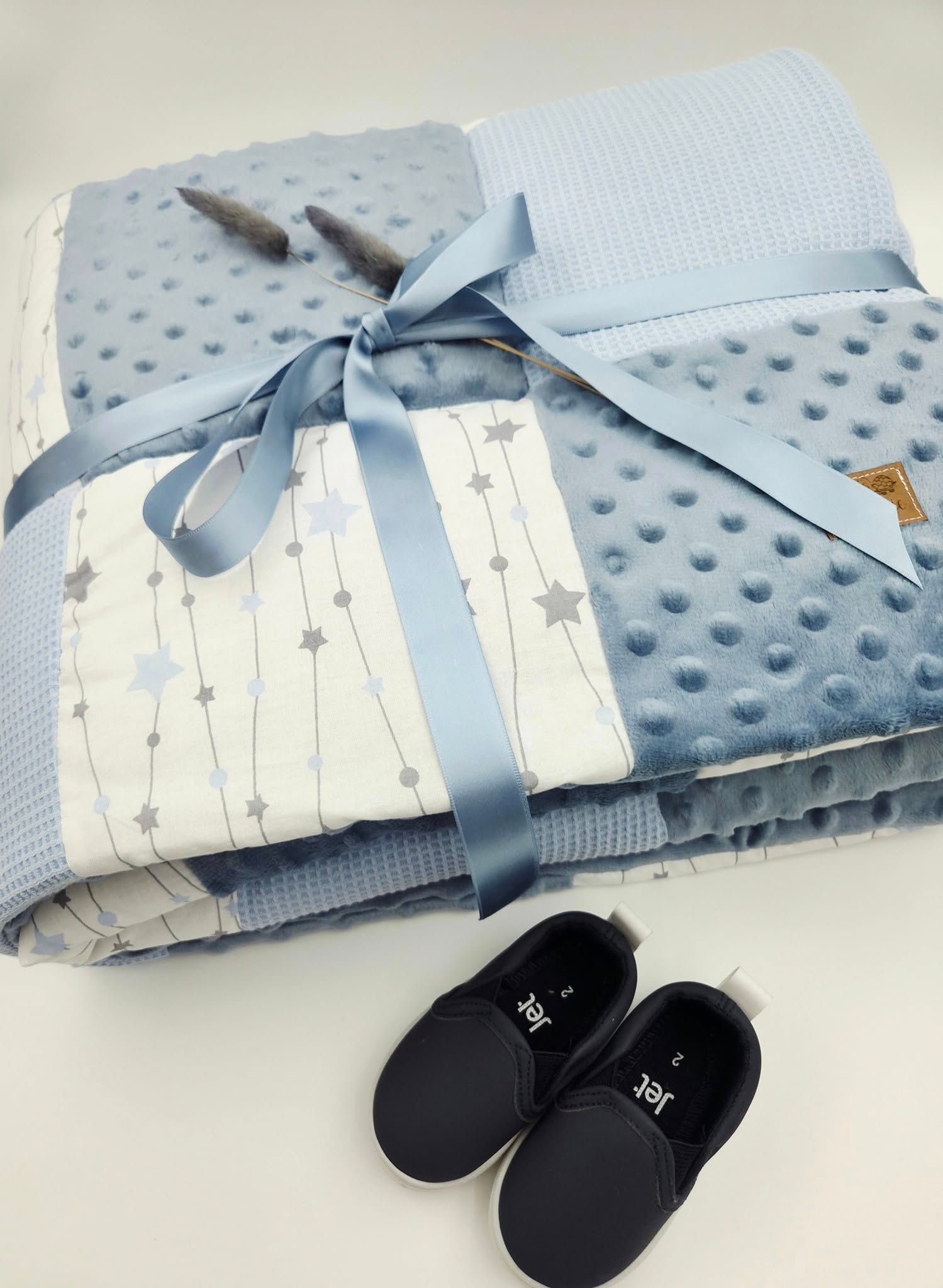 Blue and white star patterned baby blanket with minky texture and navy shoes.