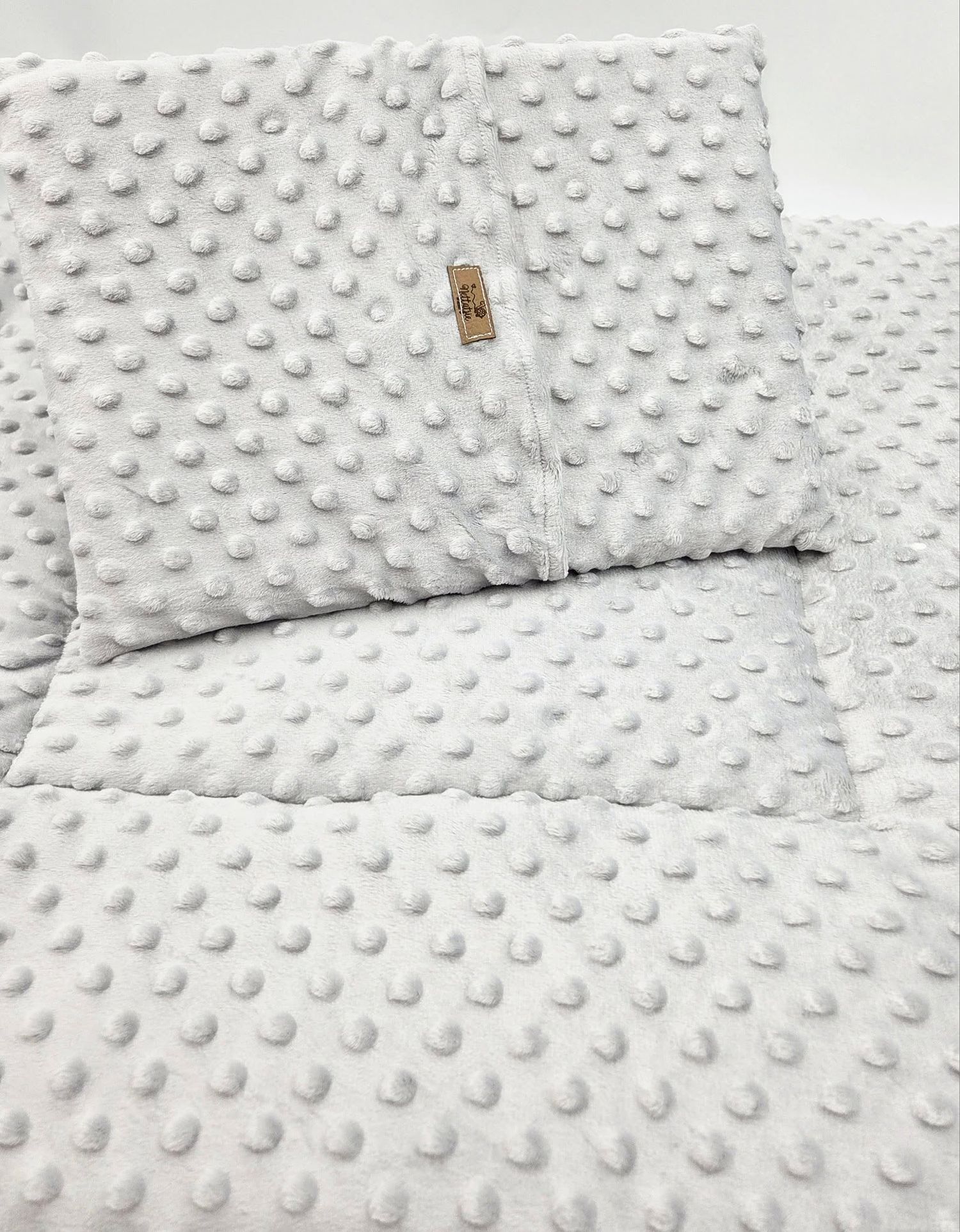 White textured minky fabric with raised dots pattern and small brand label.