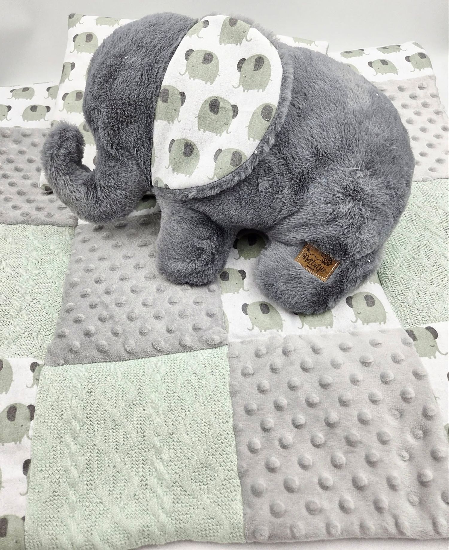 Soft gray elephant plush toy on patchwork minky blanket with elephant print.
