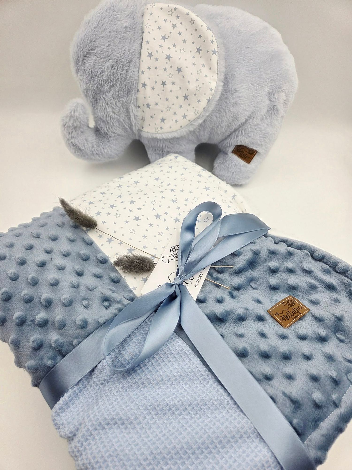 Light blue minky dot baby blanket with plush elephant toy and satin ribbon accent.