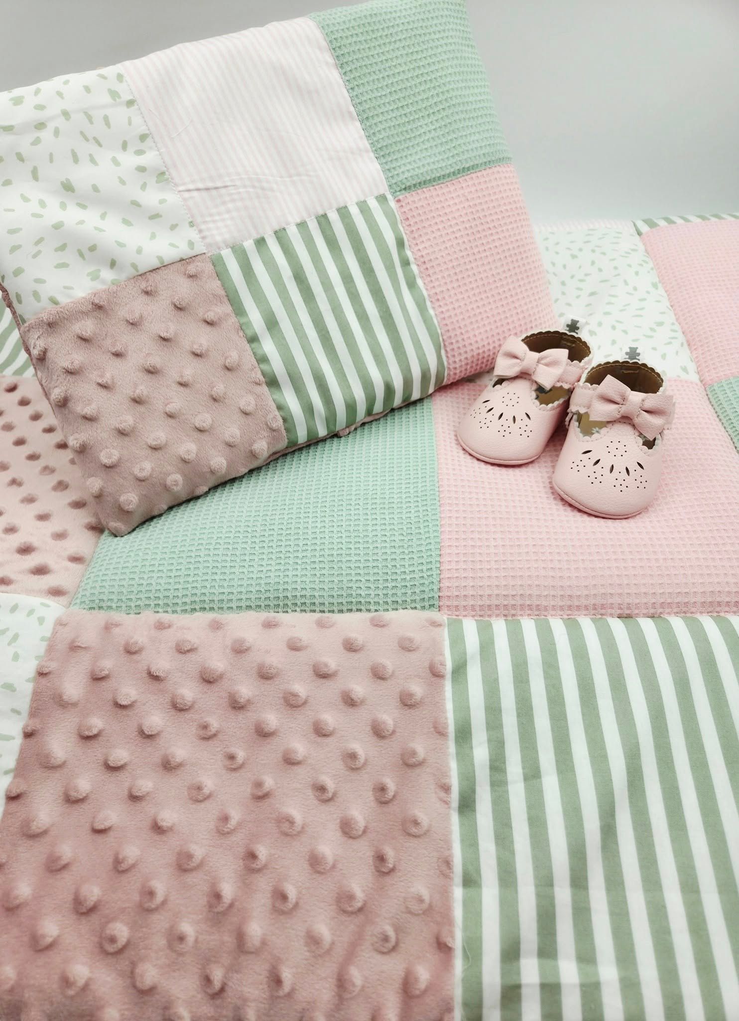 Mint green and pink patchwork baby blanket with striped pattern and dotted texture.