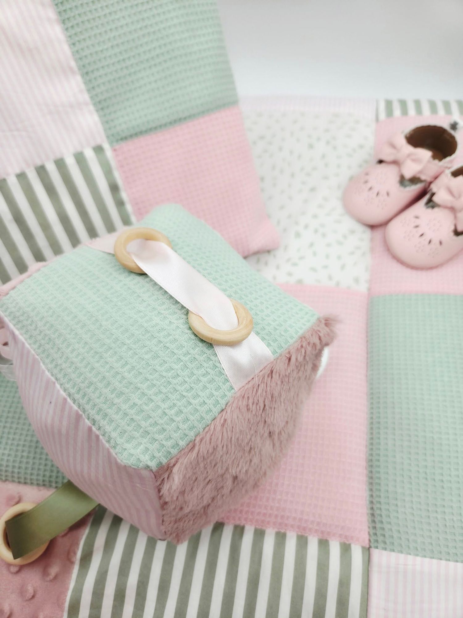 Close-up of minty green and pink textured baby blanket with decorative elements.