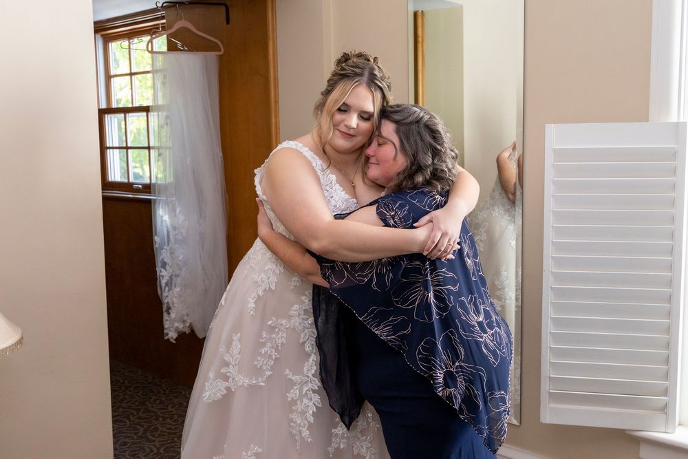 Bride in wedding dress share a tender embrace with mom in bridal suite of Polen Farm venue in Kettering Ohio.