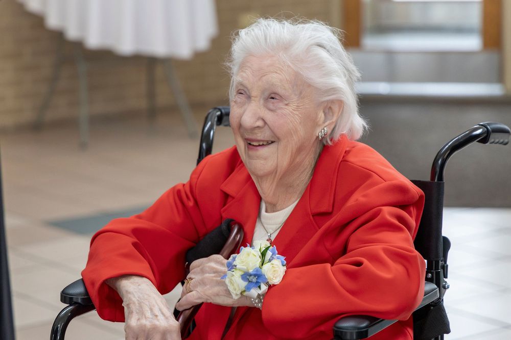 Elderly person in bright red sweater sitting in wheelchair and smiling with a festive corsage. Dayton Ohio Wedding.
