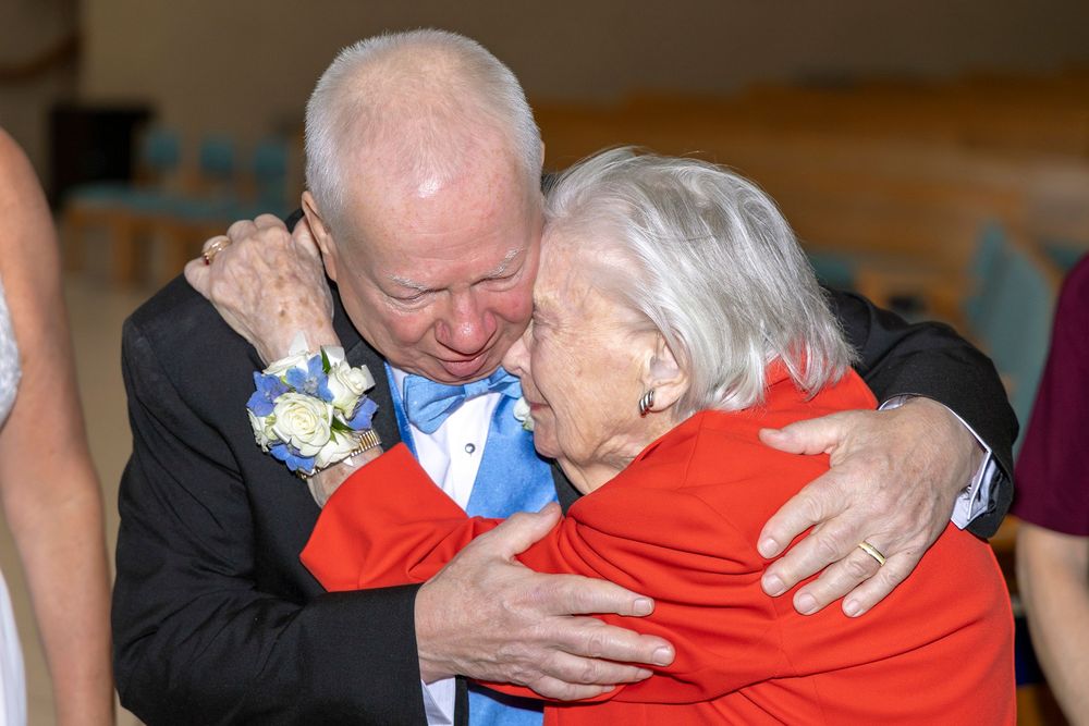 Person in black suit embraces someone wearing bright red clothing in an intimate greeting moment. Groom and his mother. Dayton Ohio Wedding.