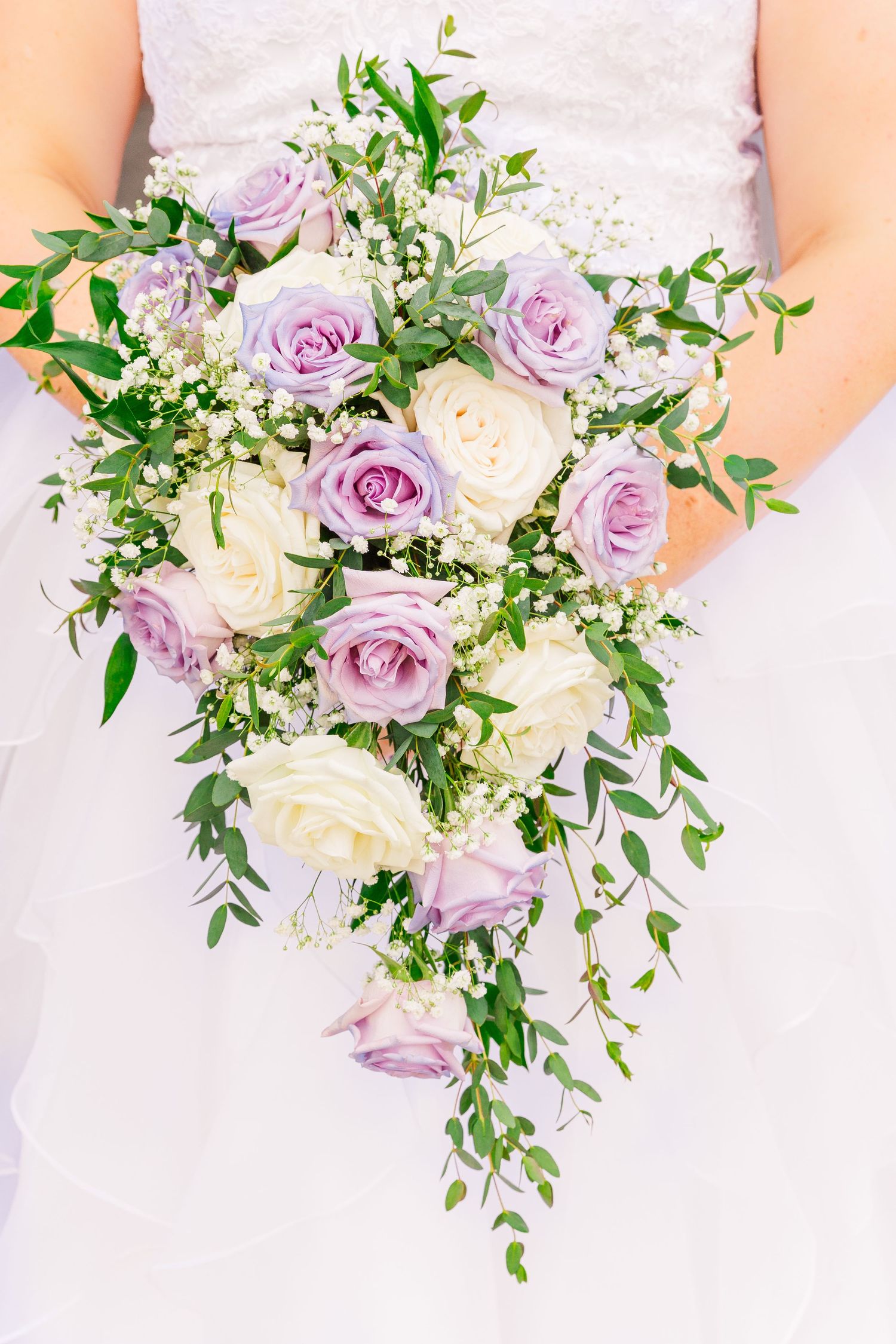 Elegant cascading bridal bouquet with lavender roses, white flowers and fresh greenery.