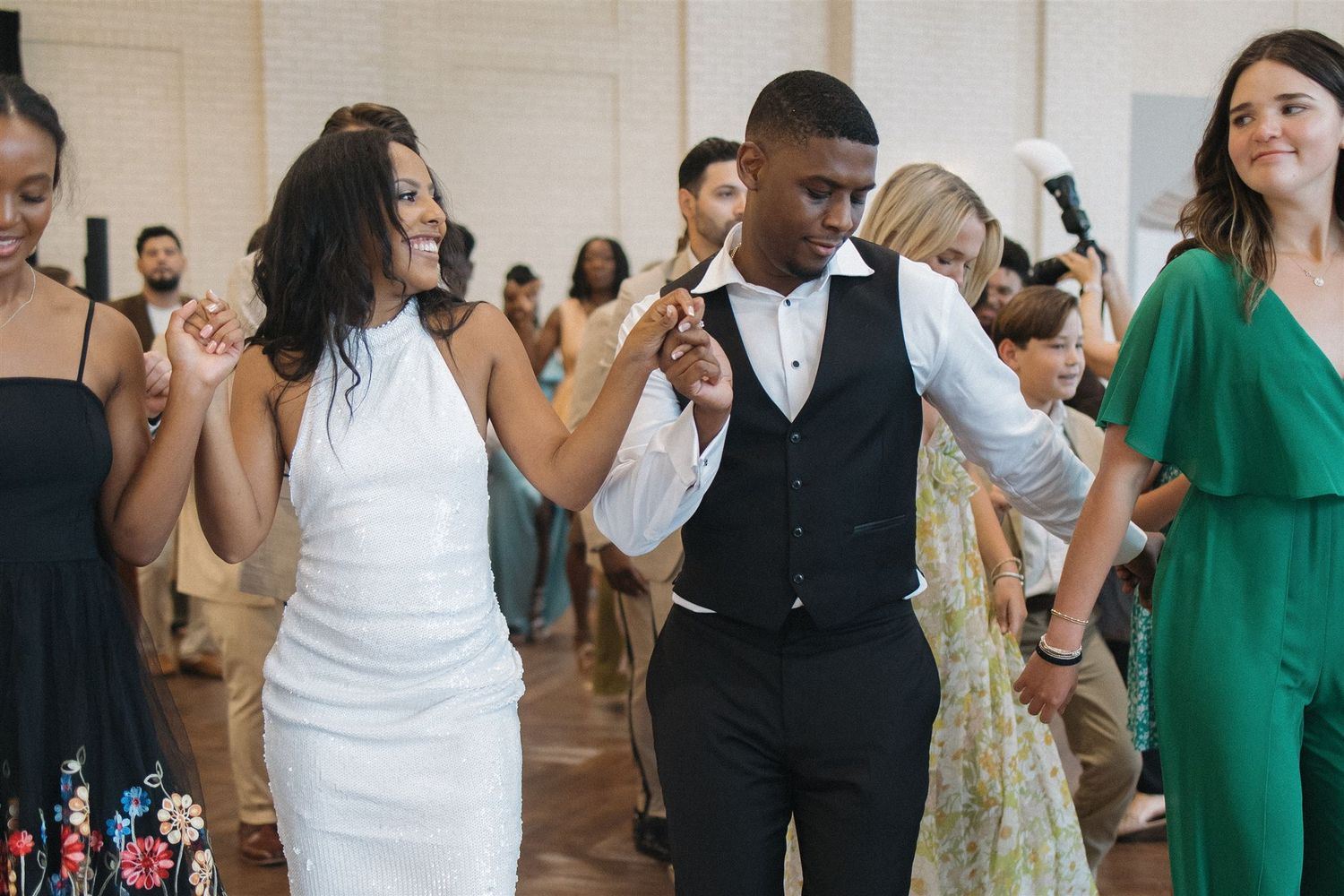 Wedding guests dancing together and enjoying celebrations on the dance floor at a reception venue.