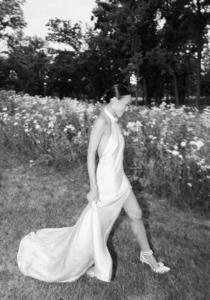 A flowing white wedding dress moves gracefully through a wildflower meadow in black and white.