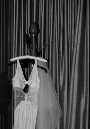 White wedding dress and veil hanging on display against striped curtain backdrop.