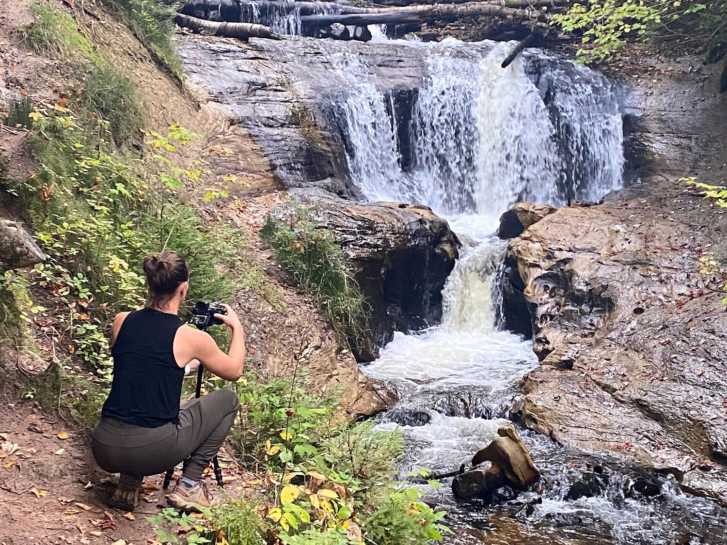 Christina Newby photographing a waterfall in a natural outdoor setting