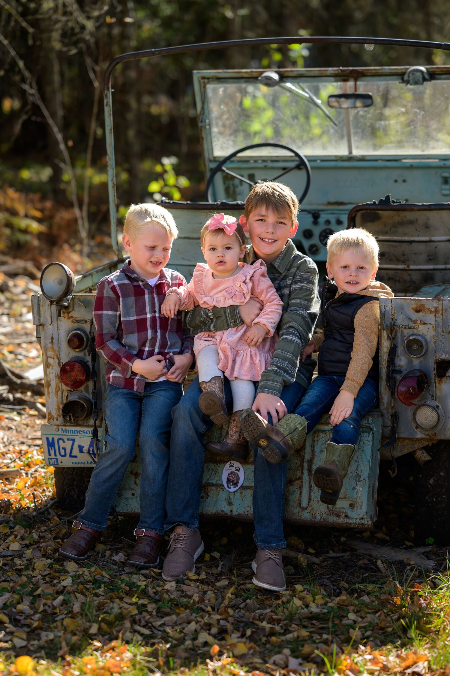 children sitting on back of rustic Jeep in fall background