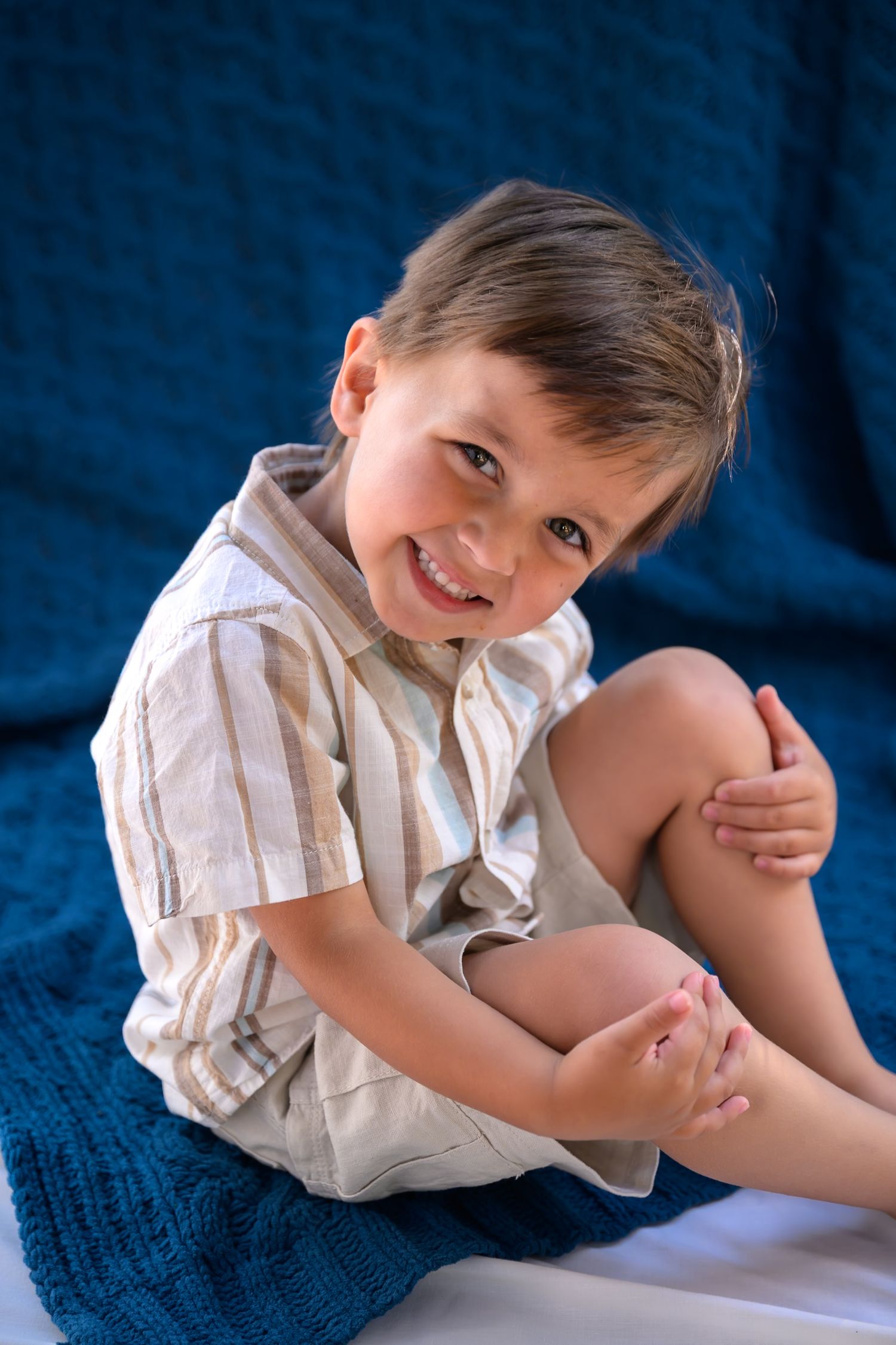 Boy poses with blue blanket in summer setting